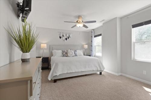 a white bedroom with a bed and a ceiling fan at Mapleton - Workfriendly, football table, yard, free parking in Indianapolis
