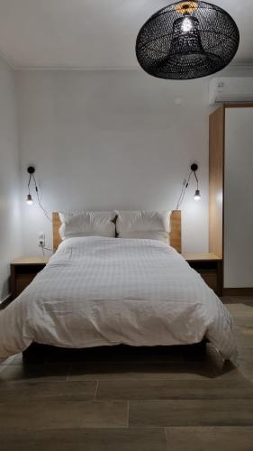 een slaapkamer met een groot wit bed met een lamp bij Averof Downtown Luxury Apartment in Ioannina