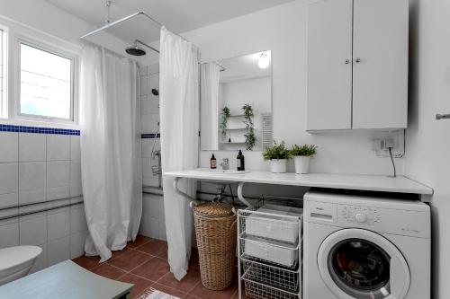 une salle de bains blanche pourvue d'un lave-linge. dans l'établissement Modern & Cozy Apartment - Downtown Reykjavik, à Reykjavik