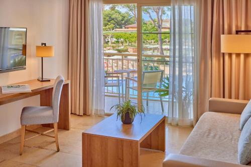 a living room with a couch and a table and a balcony at Zafiro Mallorca & Spa in Can Picafort