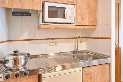 a kitchen with a sink and a microwave at Zafiro Mallorca & Spa in Can Picafort