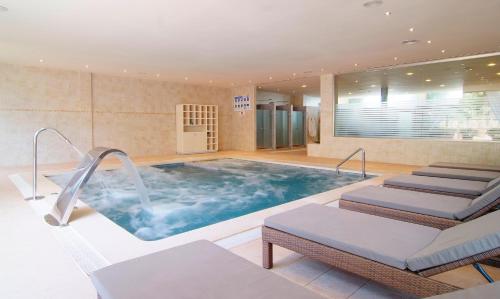 a large pool in a hotel room with chairs and a spa at Zafiro Mallorca & Spa in Can Picafort