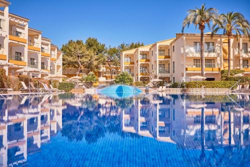 uma piscina em frente a alguns edifícios de apartamentos em Zafiro Tropic em Port d'Alcudia