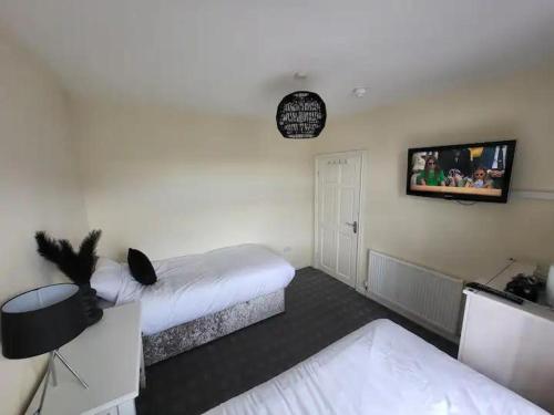 Habitación con 2 camas y TV en la pared. en The Dublin Packet - Twin Room, en Holyhead