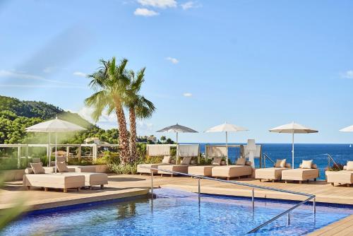uma piscina de resort com espreguiçadeiras e vista para o oceano em Zafiro Palace Andratx em Camp de Mar