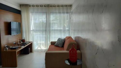 sala de estar con sofá y ventana grande en Flat Atlântico Tambaú, en João Pessoa