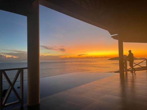 a man sitting on a porch watching the sunset at Villa Club Tropicana Carana with infinity pool in Machabee
