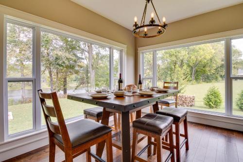 a dining room with a table and chairs and windows at Flippin Home with Deck and Grill Steps to White River in Flippin