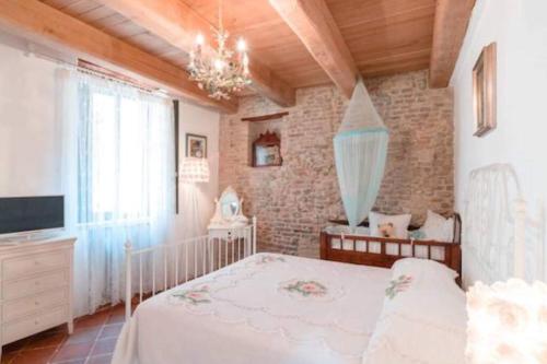 1 dormitorio con cama blanca y pared de ladrillo en Appartamento in centro storico, en San Giovanni in Marignano