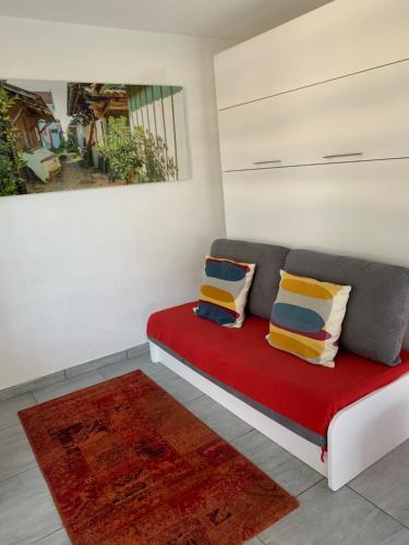 a room with a red couch with pillows and a painting at Altéa in Pessac