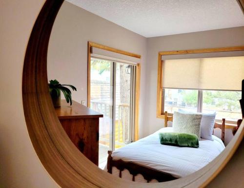 Pine Cone Cabin by FantasticStay في راديوم هوت سبرينغز: مرآة في غرفة النوم مع سرير ونافذة
