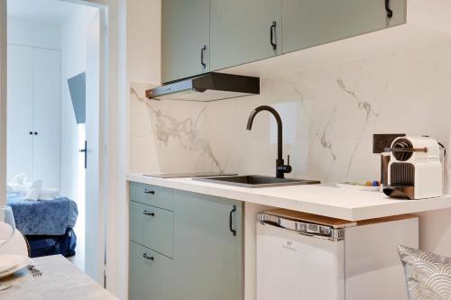 eine Küche mit weißen Schränken und einem Waschbecken in der Unterkunft Cosy Appartement Portes de Paris in Aubervilliers