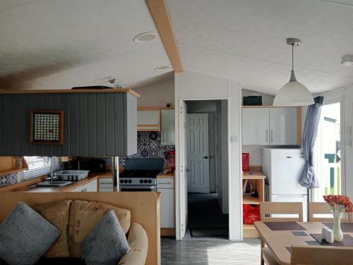 eine Küche und ein Wohnzimmer mit einem Sofa und einem Tisch in der Unterkunft 2 Bedroom 6 Birth Caravan - Towyn in Abergele