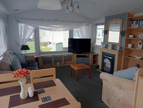 ein Wohnzimmer mit einem Sofa und einem TV in der Unterkunft 2 Bedroom 6 Birth Caravan - Towyn in Abergele