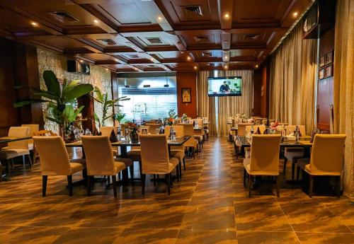 a restaurant with tables and chairs and a flat screen tv at City Tower Hotel in Fujairah