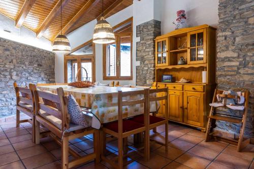 a kitchen with a table and chairs and a stone wall at Casa Conxita de Pepa in Ribera de Montardit