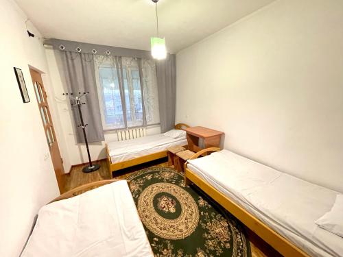 um pequeno quarto com duas camas e uma mesa em Sunny Valley Karakol em Karakol