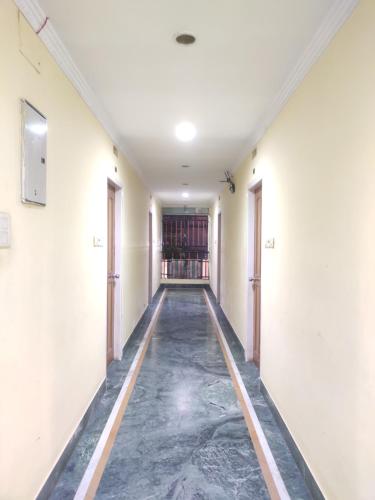 un couloir vide dans un bâtiment de bureau avec des sols en marbre dans l'établissement Phoenix Lodge, à Siliguri