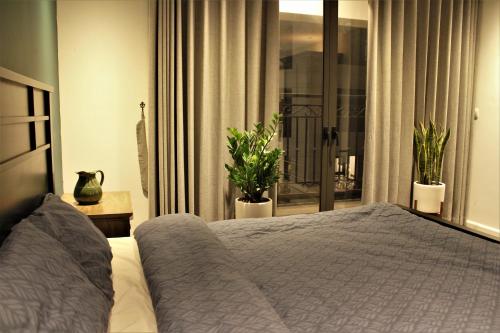 a bedroom with a bed and a window with plants at D’Leroi Soleil - Westlake Suite & Apartment in Hanoi