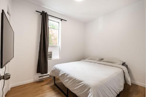 a white bedroom with a bed and a window at Appartement 1 chambre 1 lit queen-1009 in Montreal