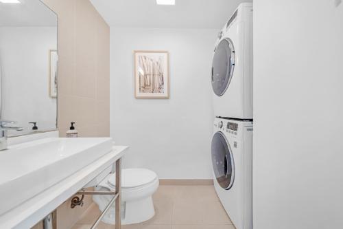 un bagno bianco con lavatrice e asciugatrice di Grove Haven Retreat a Miami