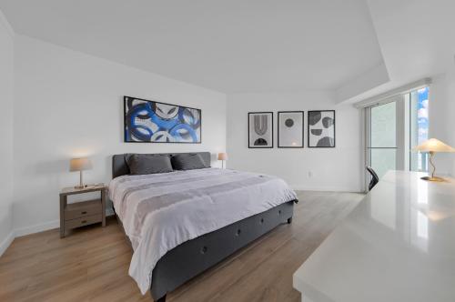 a white bedroom with a large bed and a table at Grove Haven Retreat in Miami