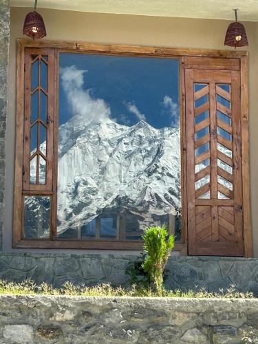 a window with a reflection of a snow covered mountain at applegardenhunza in Alīābād