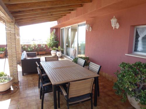 een patio met een houten tafel en stoelen bij Espectacular terraza y vistas en 1a línea de playa in Cullera