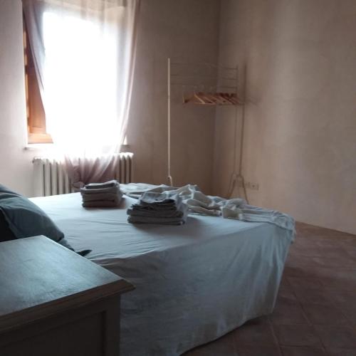 a bedroom with a bed with white sheets and a window at B&B Casale Ormano in San Venanzo