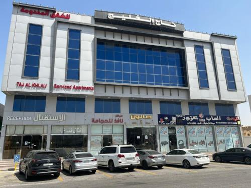 a building with cars parked in a parking lot at تاج الخليج للشقق المخدومة in Dammam