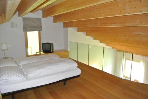 a bedroom with a white bed and wooden floors at Chesa La Montanella - Ferienwohnung, Maloja in Maloja