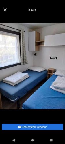 deux lits dans une chambre avec une fenêtre dans l'établissement Mobilhome Bonne Anse plage La Palmyre, aux Mathes
