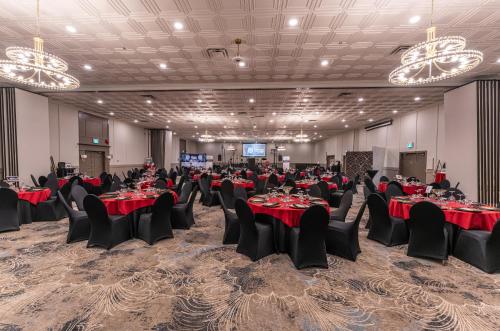 a banquet hall with red tables and chairs and chandeliers at Prestige Vernon Lodge in Vernon