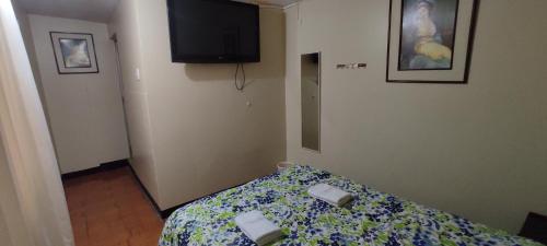 a bedroom with a bed and a tv on the wall at Aruba Suite Hotel in Lima