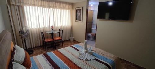 a bedroom with a bed and a table and a television at Aruba Suite Hotel in Lima