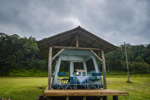 a tent with chairs and a table in a field at Recanto do Vale Glamping in Pomerode