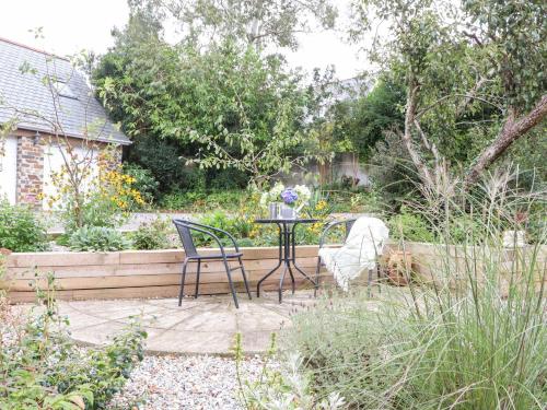 a table and chairs in a garden with a dog at Little Polgray in St Austell