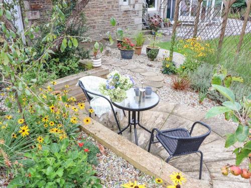a garden with a table and chairs and flowers at Little Polgray in St Austell