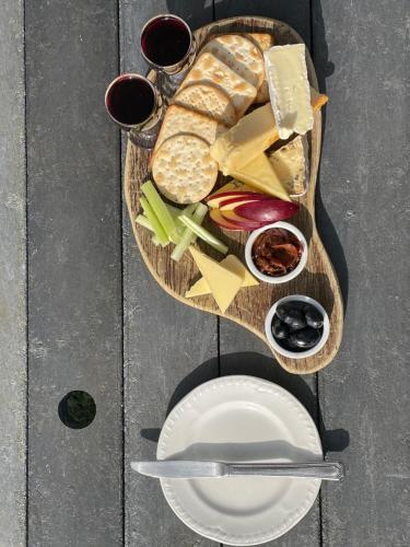 a table with a plate of cheese and bread and two glasses of wine at The Fat Lamb Country Inn and Nature Reserve in Ravenstonedale