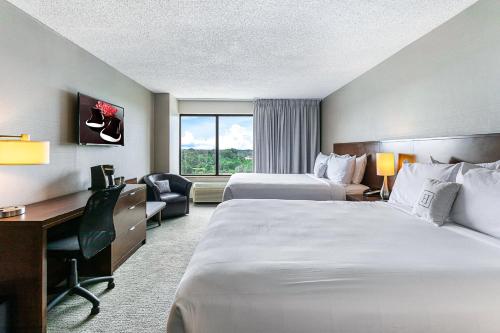 a hotel room with two beds and a desk at Harborside Hotel in Oxon Hill