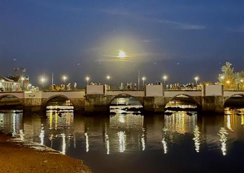 a bridge over a river at night with people on it at Golden Club- Eyes on Sea in Cabanas de Tavira