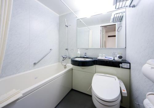a white bathroom with a toilet and a sink at Daiwa Roynet Hotel Kobe Sannomiya in Kobe