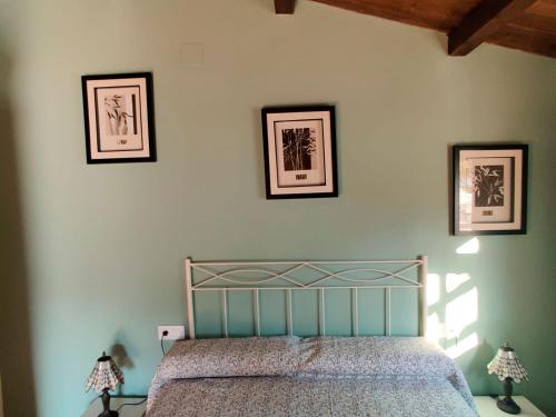 1 dormitorio con 1 cama con 3 cuadros en la pared en Casa Rural en Yeguada Vistabella., en Enguera