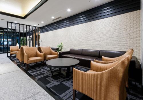 a waiting room with a leather couch and chairs at Daiwa Roynet Hotel Kobe Sannomiya in Kobe