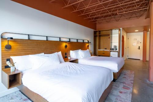 two beds in a hotel room with white sheets at The Myriad Hotel Louisville, Tapestry Collection by Hilton in Louisville