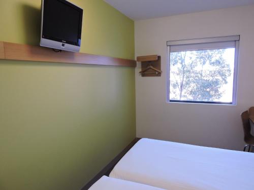 um quarto com uma cama e uma televisão na parede em ibis Budget Sydney Olympic Park em Sydney