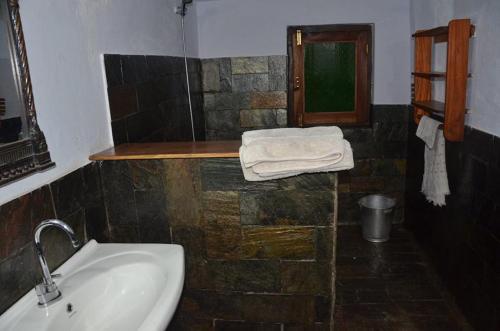 bagno con lavandino, specchio e asciugamani di Shivanandi River Lodge a Rudraprayāg