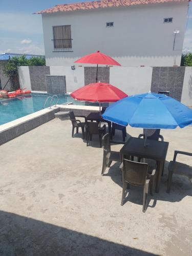 吉拉爾的住宿－Casa Vacacional Quinta Sofia，一组桌子,在游泳池旁边配有遮阳伞