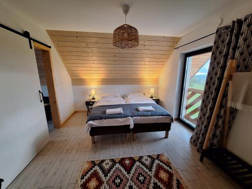 a bedroom with a bed and a large window at Domki Szczyt Beztroski - Sauna, Jacuzzi in Nowy Targ