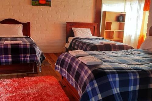 a bedroom with two beds and a red rug at Casa de campo con hermosa vista in Riobamba